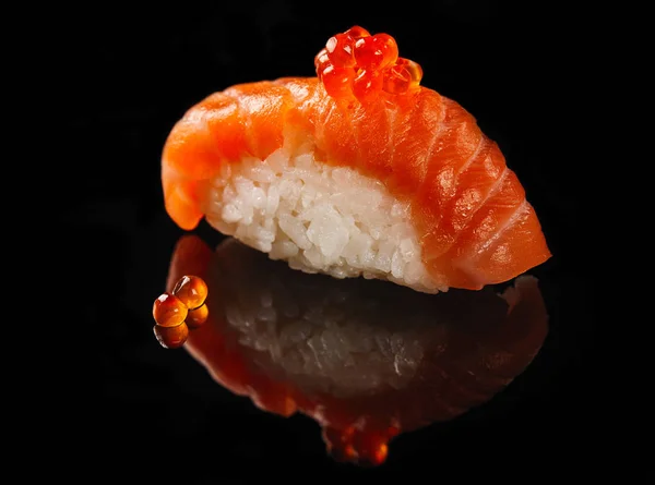 Nigiri med solomon og rød kaviar på svart bakgrunn med refleksjon – stockfoto