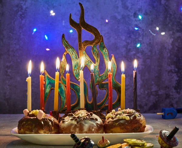 Férias judaicas Hanukkah fundo. Um prato tradicional é donuts doces. Mesa Hanukkah definir um castiçal com velas e spinning tops em um fundo azul. Iluminando velas Chanukah — Fotografia de Stock