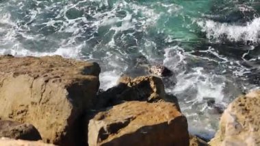 Güneşli bir günde Tel Aviv bölgesindeki Akdeniz taşlarında sörf yapmak.