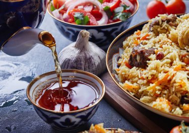 Özbek pilavı otantik mavi ve altın kaplamalı, domates, sarımsak ve çayla mavi arka planda çekilen