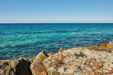 Akdeniz 'de, güneşli bir Kasım gününde taşlara, yatlara ve teknelere vuran dalgalarla