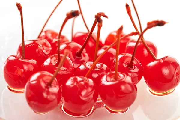 Cerezas azucareras con ramitas sobre un plato transparente sobre un fondo claro — Foto de Stock