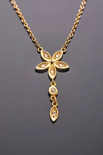 Fabrication de bijoux. Pendentif en or jaune en forme de fleur à cinq feuilles avec diamants sur fond gris — Photo