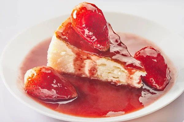 Cheesecake cu gem de căpșuni pe o placă albă pe un fundal deschis — Fotografie, imagine de stoc