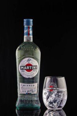 Martini şişesi ve buzlu martini bardağı. Siyah bir arka planda yansıması var..