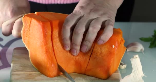 Vrouw snijdt een pompoen op een houten bord in de keuken. Vrouwelijke handen bereiden roomsoep met pompoen. Gezond eten concept — Stockvideo