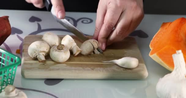 Kadın mutfaktaki ahşap bir tahtanın üzerinde mantar dilimliyor. Kadın elleri balkabağı ve mantarlı krema çorbası hazırlar. Sağlıklı beslenme. — Stok video