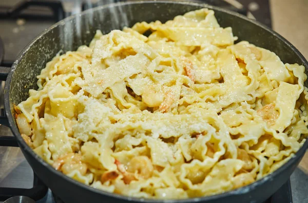 Gamberetti fritti con pasta italiana chiamata mafaldine in una padella cosparsa di parmigiano — Foto Stock