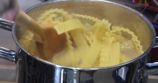 女人搅拌意大利面食 Mafaldine 锅里放着炸虾仁 — 图库视频影像