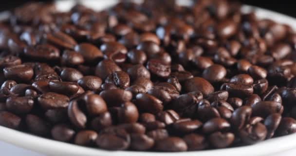 Fragrant coffee beans spin in a white plate of slow motion — Stock Video