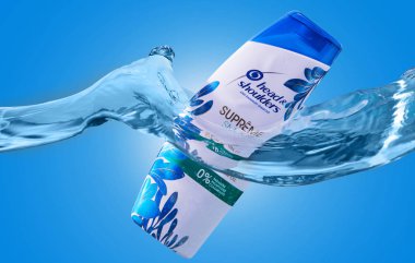 Mavi-beyaz bir şişede şampuan, mavi arka planda bir dalgayla suda..