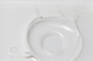 Taze süt, süt havuzunda bir taç sıçraması yapıyor. Üst görünüm, gri-beyaz arkaplanda izole edilmiş