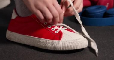 Bir kadın antrenmandan önce spor ayakkabısına dantel bağlar..