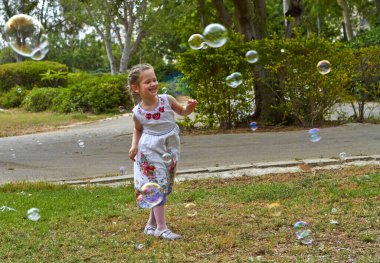 Güneşli bir gün Bir sürü sabun köpüğü olan mutlu küçük bir kız
