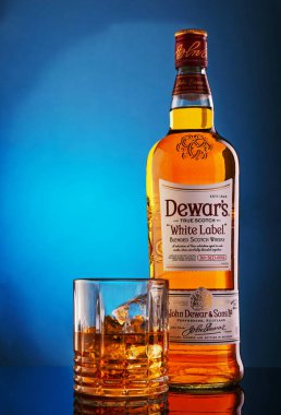 Tel Aviv, İsrail - 12 Mart 2020: Viski ve buzla kaplı şişe ve cam mavi bir zemin üzerinde eğim ve yansıma.