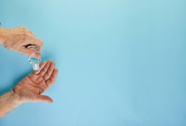 Coronavirus COVID-19 konsepti, kendinizi enfeksiyondan nasıl koruyacağınız. El dezenfeksiyonu, jel sıkmak, maske takmak ve eline hap sıkmak demektir. Mavi bir arka planda düz uzandı.