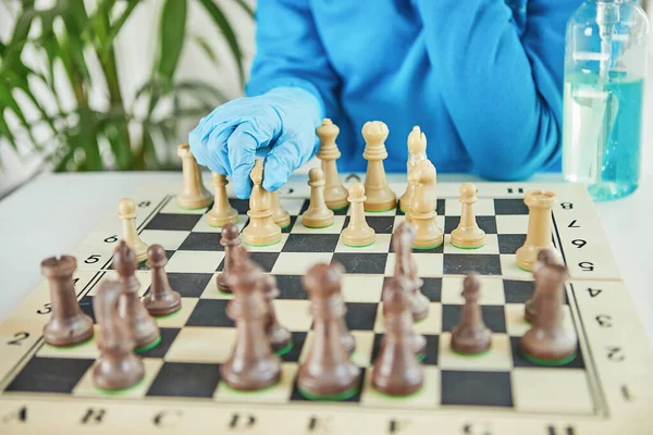 Life in quarantine coronavirus: games and activities for the kids at home during quarantine covid-19. A teenage girl in a mask and gloves plays chess. Selective focus. Close up.