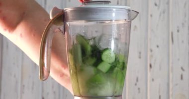 Kadın blender 'ı yeşil meyve suyu için malzemelerle çeviriyor. Yavaş çekimde karıştırma.