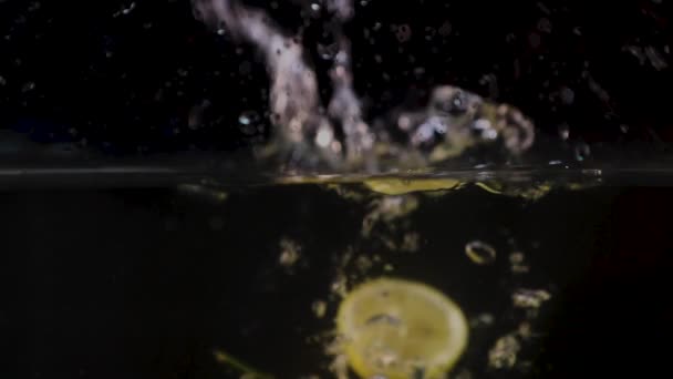レモンとレモンのスライスはスプラッシュで水の中に落ちます スローモーション — ストック動画