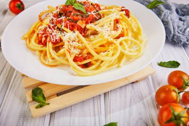 Lezzetli iştah açıcı klasik İtalyan spagettisi domates soslu, parmesanlı ve fesleğenli hafif ahşap arka planda. Yan görüş. Uzayı yakın plan kopyala