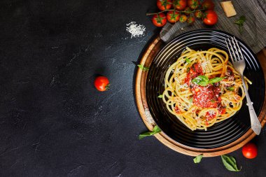 Lezzetli iştah açıcı klasik İtalyan makarnası domates soslu, parmesanlı ve fesleğenli karanlık bir masada. Üst manzara, yatay. Düz yatıyordu. Boşluğu kopyala.