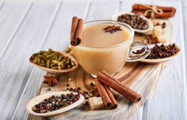 Geleneksel Hint içkisi. Baharatlı Masala çayı. Tarçın, kakule, anason, şeker, karanfil, hafif ahşap arka planda biber. Uzayı kopyala Yan görünüm