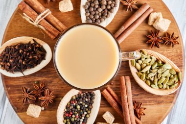 Geleneksel Hint içkisi. Baharatlı Masala çayı. Tarçın, kakule, anason, şeker, karanfil, hafif ahşap arka planda biber. Uzayı kopyala Düz yatıyordu. Kopyala.