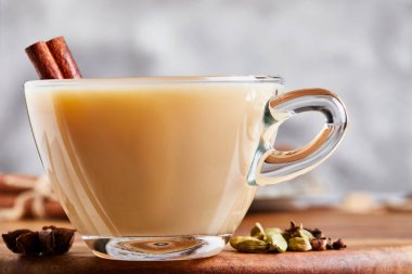 Geleneksel Hint içkisi. Baharatlı Masala çayı. Tarçın, kakule, anason, şeker, karanfil, hafif ahşap arka planda biber. Uzayı kopyala Yan görünüm