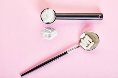 Kolajen tozu ve pembe arka planda haplar. Fazladan protein alımı. Cilt, kemik, eklemler ve bağırsaklar için doğal güzellik ve sağlık desteği. Bitki ya da balık bazlı. Üst Manzara. Boşluğu kopyala.