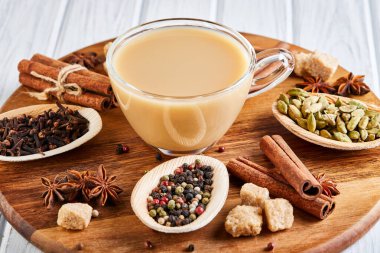 Geleneksel Hint içkisi. Baharatlı Masala çayı. Tarçın, kakule, anason, şeker, karanfil, hafif ahşap arka planda biber. Uzayı kopyala Yan görünüm