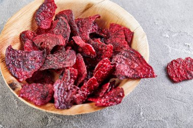 Diyet sağlıklı yeme konsepti. Kurutulmuş pancar cipsi ya da ahşap bir kasede, gri beton arka planda pişmiş pancar. Organik doğal gıdalar. Boşluğu kopyala.