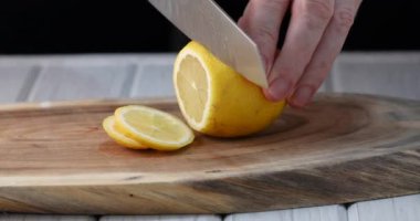 Bir adam ahşap arka planda bir limonu dilimlere ayırıyor. 4k video