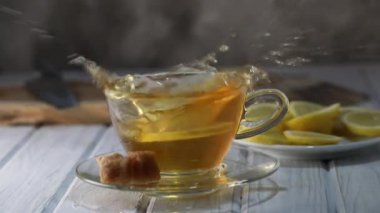 Limon dilimi yavaş çekimde bir fincan sıcak çaya düşer.