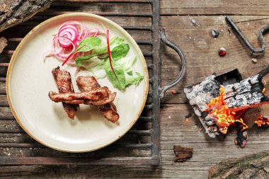 Köy usulü ızgara domuz eti ve eski ahşap masa. Ateşin içinde kömür BBC yemeği