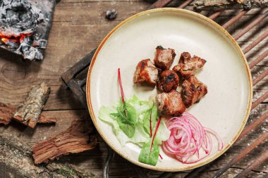 Köy usulü ızgara domuz eti ve eski ahşap masa. Ateşin içinde kömür BBC yemeği