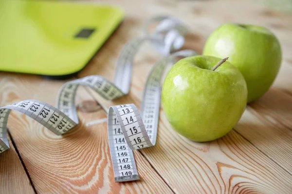 Healthy diet and diet for weight loss, scales, apples and tape measure on wooden background. Vegetarian food