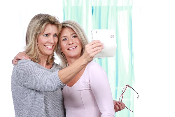Две счастливые зрелые женщины делают селфи со смартфоном — стоковое фото