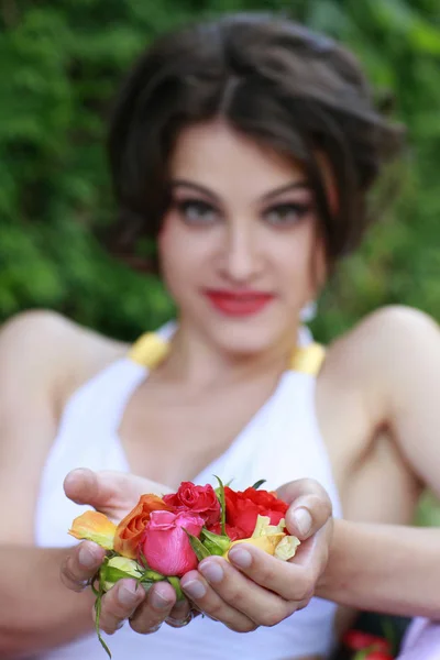 Ελκυστική γυναίκα παρουσιάζει τριαντάφυλλα στα χέρια της — Φωτογραφία Αρχείου