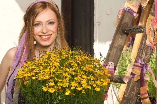 Mulher atraente com planta de flor amarela — Fotografia de Stock