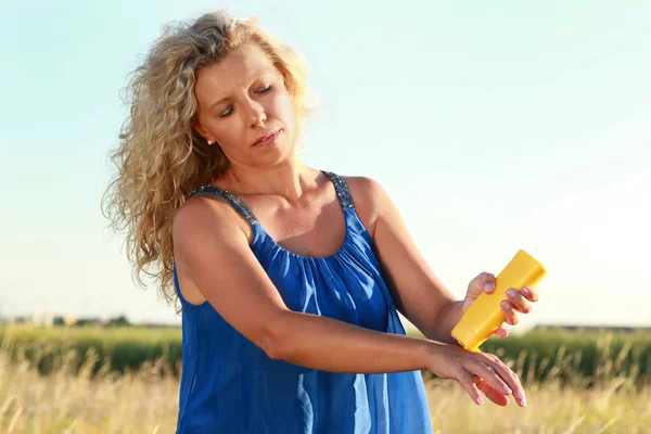 Rijpe vrouw geldt zonnebrandcrème — Stockfoto