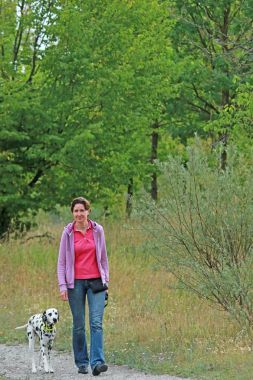 Olgun kadın doğa ortamında bir Dalmaçyalı köpek yürüyor