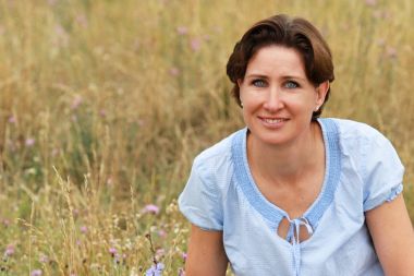 Olgun kadın yaz aylarında çiçek alanında oturuyor