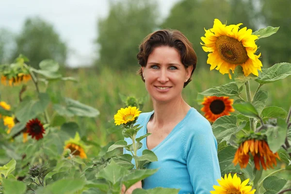 Mature woman standing in a sunflower field — Stock Photo, Image
