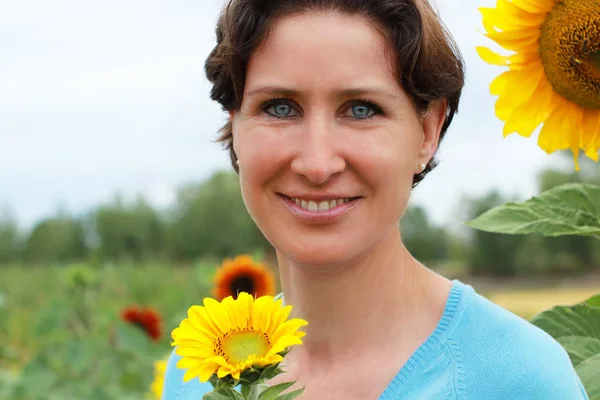 Reife Frau steht in einem Sonnenblumenfeld — Stockfoto