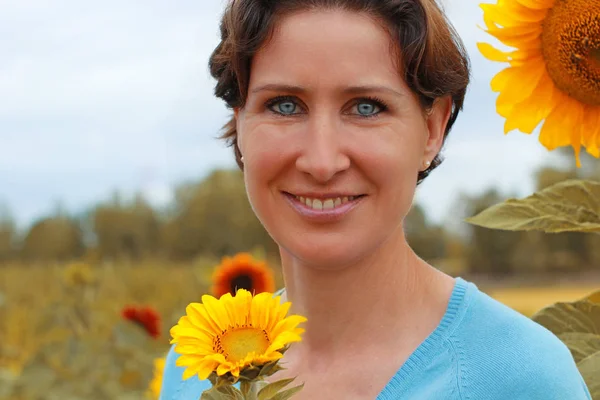 Reife Frau steht in einem Sonnenblumenfeld — Stockfoto