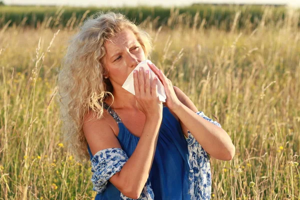 Mature woman with handkerchief blows her nose — Stock Photo, Image