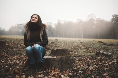 Ağaç gövdesi oturan genç kadın