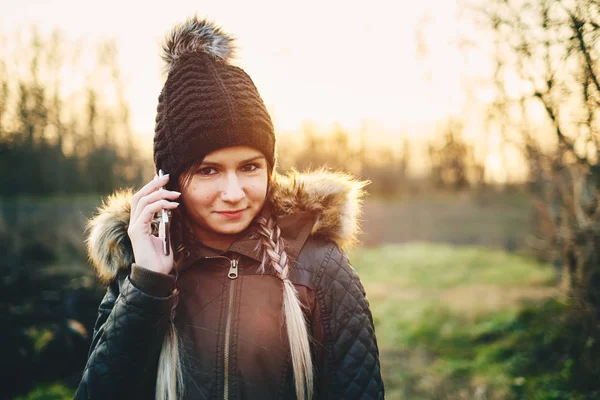 Молодая женщина звонит с мобильного телефона на открытом воздухе в зимний период — стоковое фото