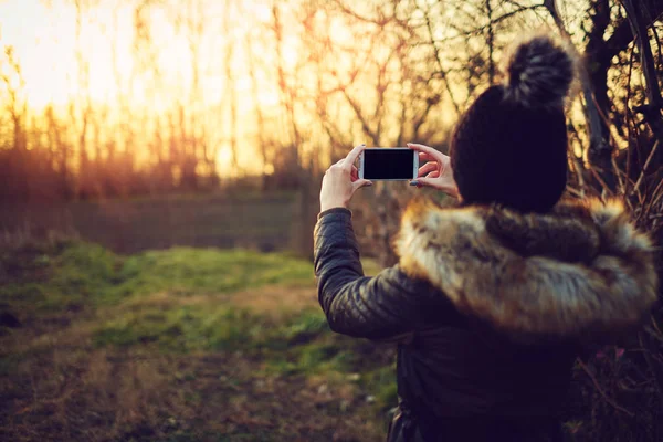 Mujer atractiva joven tomando fotos con teléfono inteligente — Foto de Stock