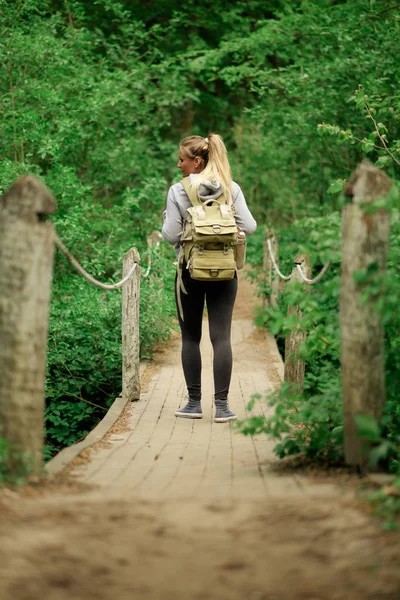 Mujer excursionista en puente forestal — Foto de Stock